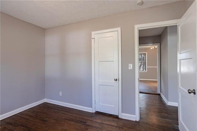 empty room featuring a textured ceiling and dark hardwood / wood-style flooring