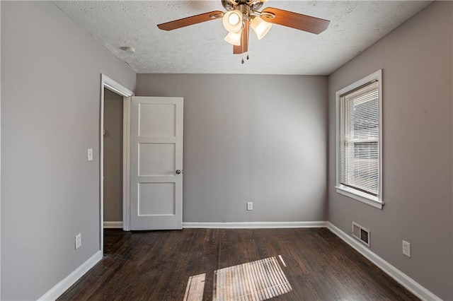 empty room featuring ceiling fan, dark wood-type flooring, and a textured ceiling