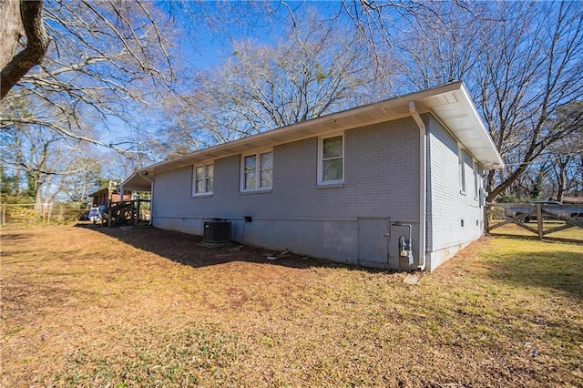 view of side of home featuring a lawn and central AC