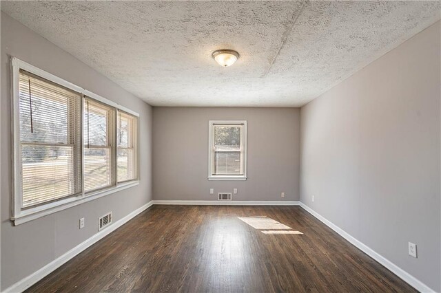 spare room featuring dark wood-type flooring and a textured ceiling