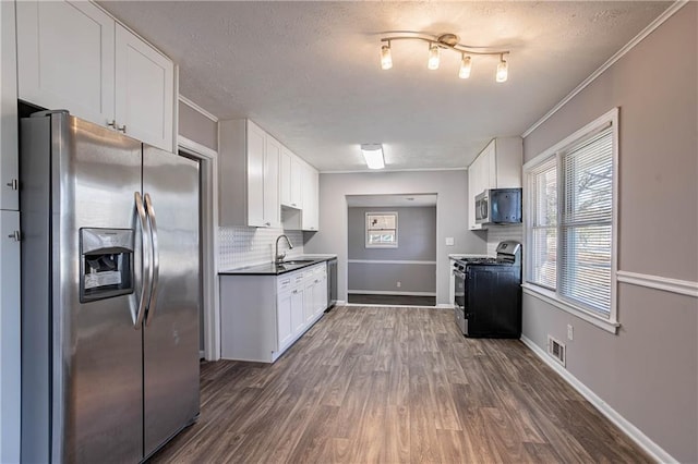kitchen featuring appliances with stainless steel finishes, white cabinetry, dark hardwood / wood-style flooring, tasteful backsplash, and sink