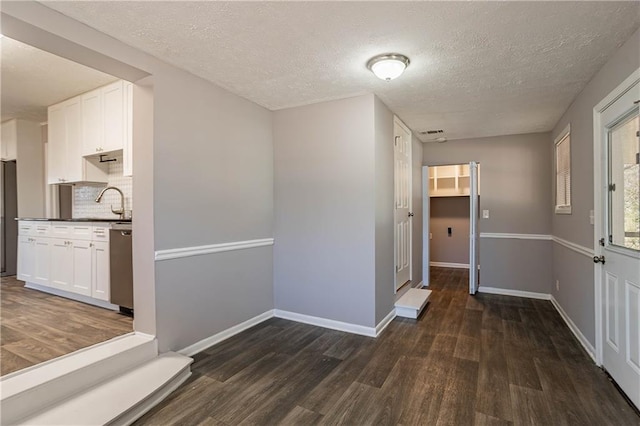 hall with a textured ceiling and dark hardwood / wood-style flooring