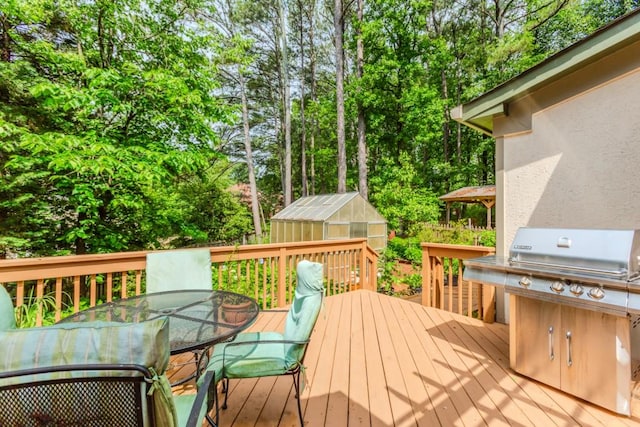 529 Arnold Rd, Lawrenceville, GA 30044 - deck with outdoor dining area, a greenhouse, an outdoor structure, a grill, and view of scattered trees