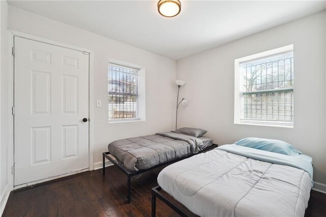 bedroom with dark hardwood / wood-style flooring and multiple windows