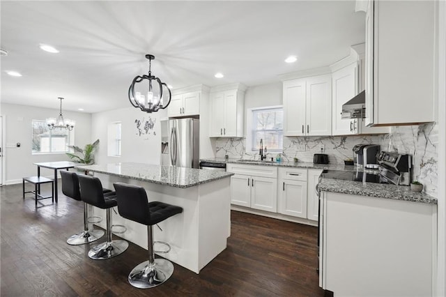 kitchen with a wealth of natural light, white cabinetry, a center island, and stainless steel appliances