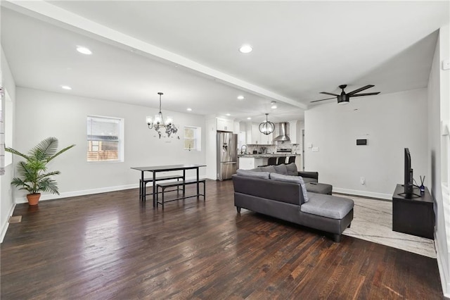 living room featuring beamed ceiling, dark wood-type flooring, and ceiling fan with notable chandelier