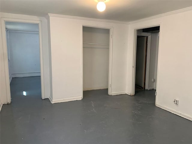 unfurnished bedroom with crown molding, finished concrete flooring, a closet, and baseboards