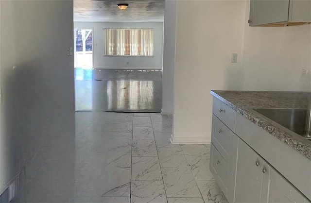 kitchen with baseboards and marble finish floor