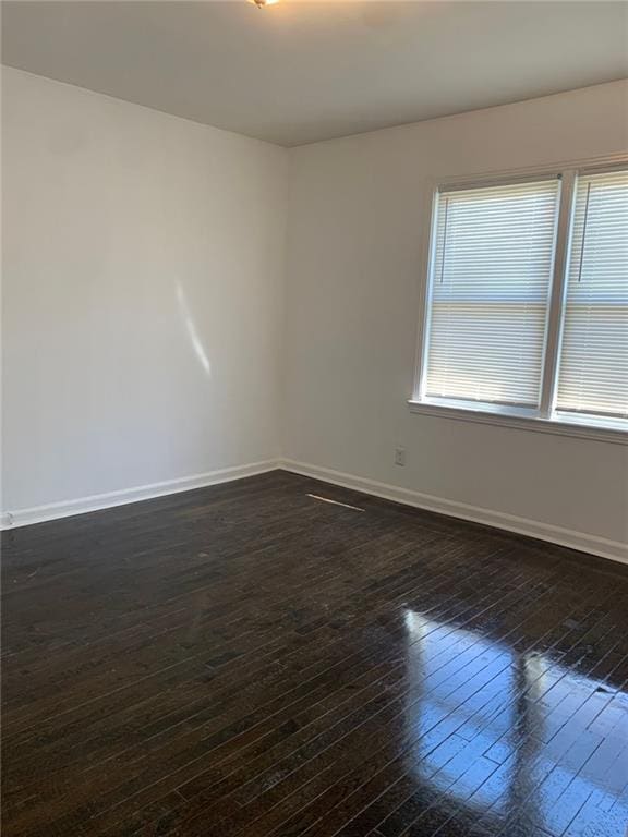 spare room with dark wood finished floors and baseboards