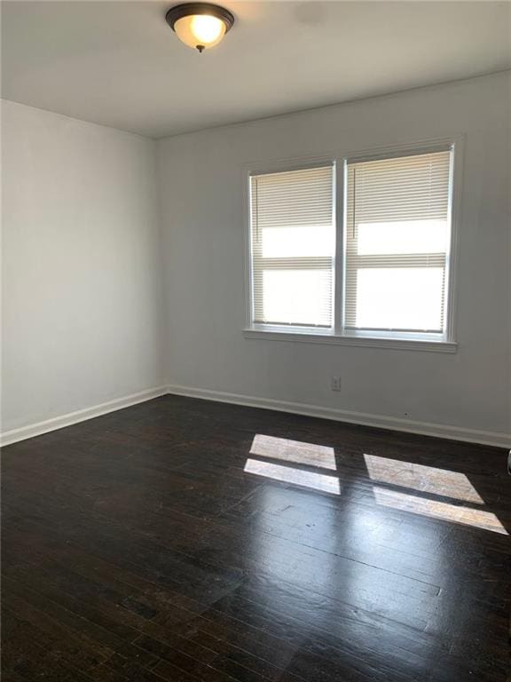 empty room with dark wood-style floors and baseboards