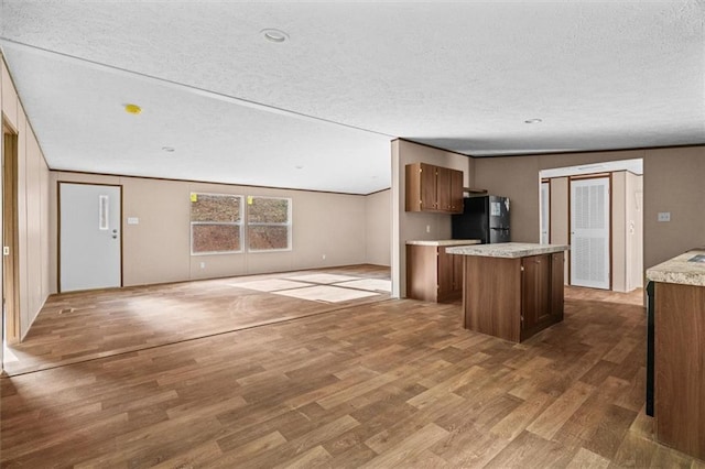 211 Fire Tower Rd NE, Calhoun, GA 30701 - kitchen featuring a kitchen island, wood finished floors, light countertops, freestanding refrigerator, and a textured ceiling