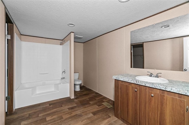 211 Fire Tower Rd NE, Calhoun, GA 30701 - bathroom with vanity, wood finished floors, toilet, a textured ceiling, and washtub / shower combination