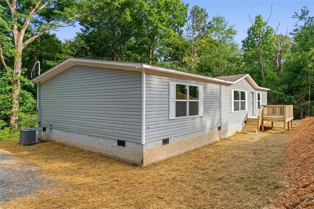 211 Fire Tower Rd NE, Calhoun, GA 30701 - view of home's exterior with crawl space, central air condition unit, a deck, and view of wooded area