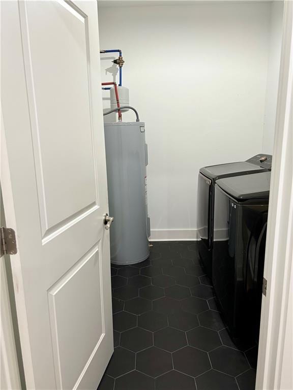 washroom with washer and dryer, electric water heater, and dark tile patterned floors