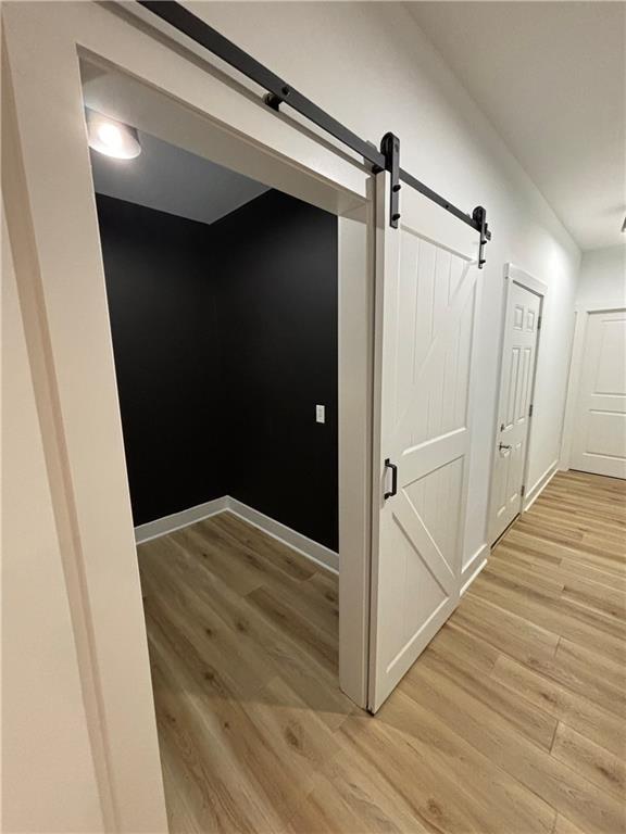 hallway with light wood-type flooring and a barn door