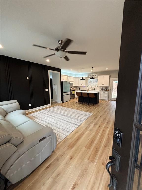 living room with ceiling fan and light hardwood / wood-style flooring