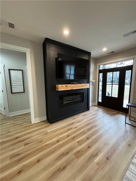 unfurnished living room featuring a large fireplace and light hardwood / wood-style floors