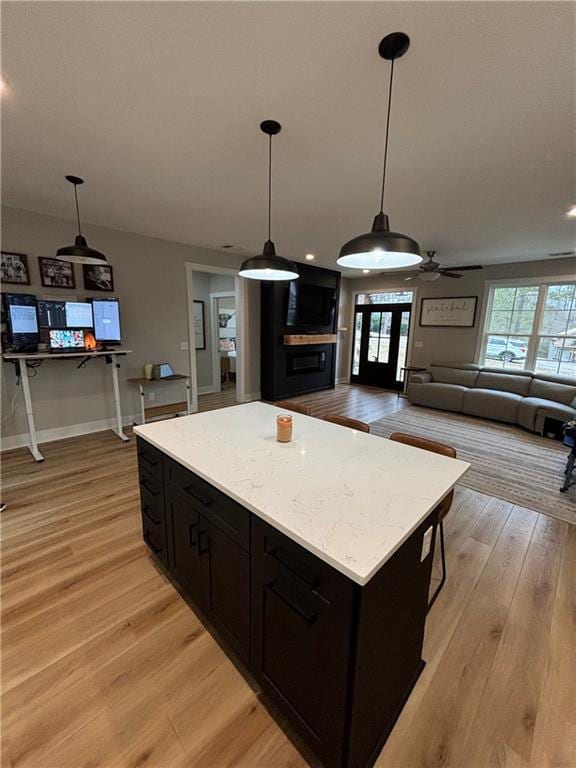 kitchen with ceiling fan, a kitchen island, pendant lighting, and light wood-type flooring