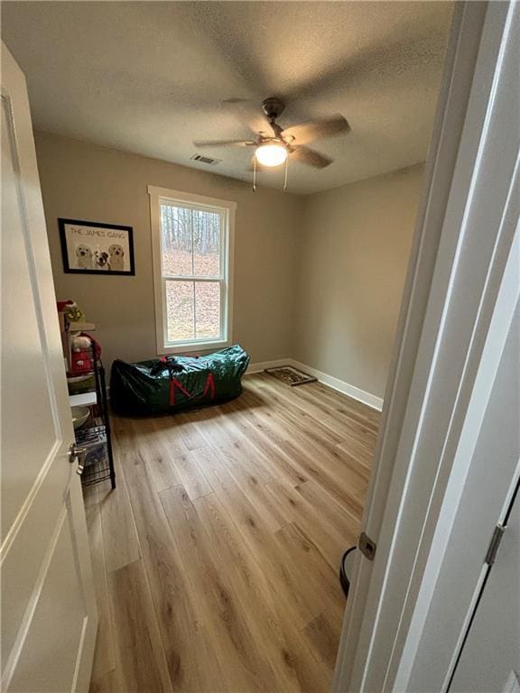 bedroom featuring ceiling fan, light wood-type flooring, and a textured ceiling