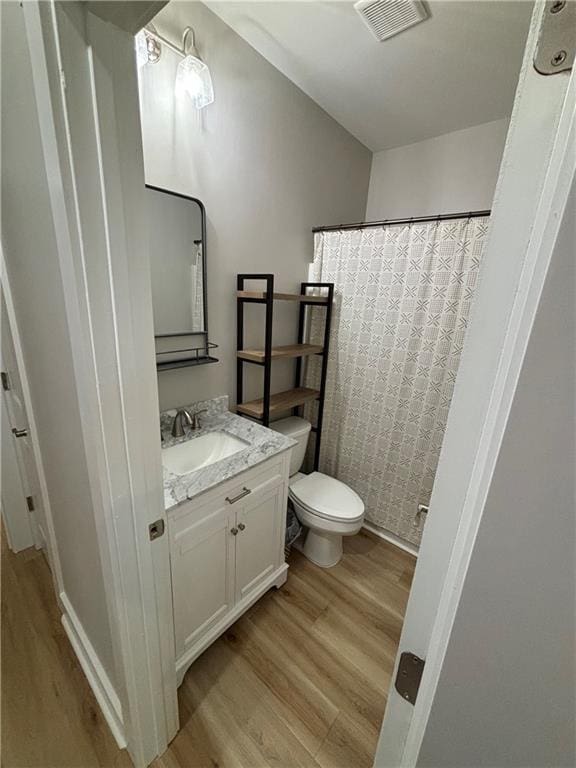 bathroom featuring a shower with curtain, vanity, wood-type flooring, and toilet