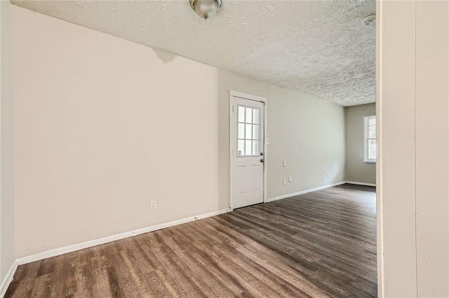 unfurnished room with a textured ceiling and dark hardwood / wood-style flooring