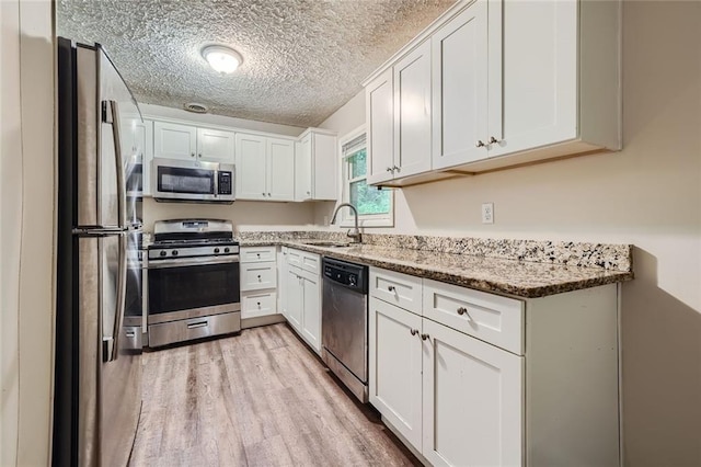 kitchen featuring sink, light stone counters, stainless steel appliances, and white cabinets