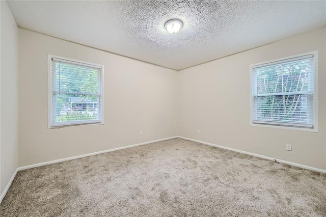 carpeted empty room with a textured ceiling