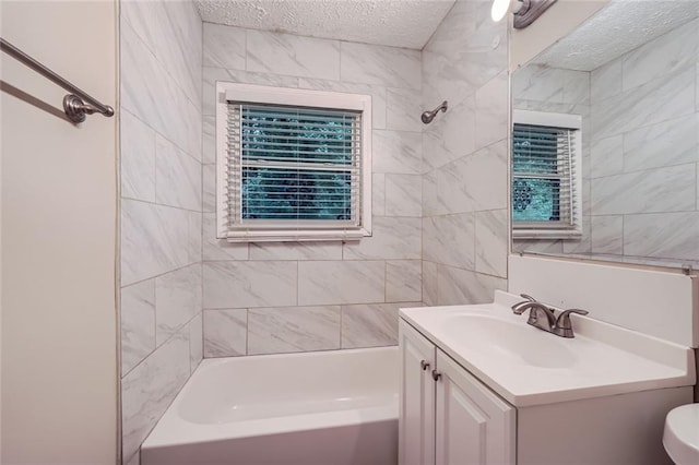 full bathroom featuring tiled shower / bath, vanity, a textured ceiling, and toilet