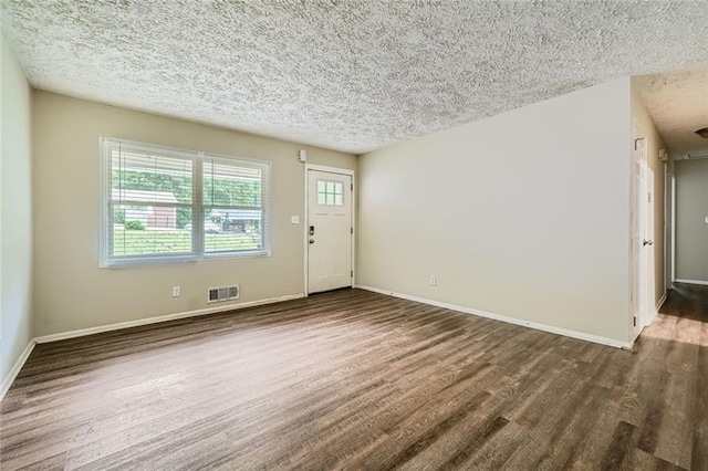 empty room featuring dark hardwood / wood-style flooring and a textured ceiling