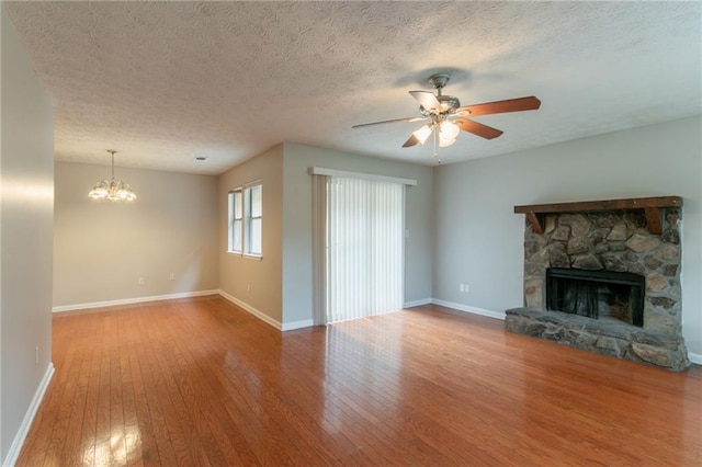 1615 Enchanted Forest Dr, Conley, GA 30288 - unfurnished living room featuring a fireplace, baseboards, wood-type flooring, and ceiling fan with notable chandelier