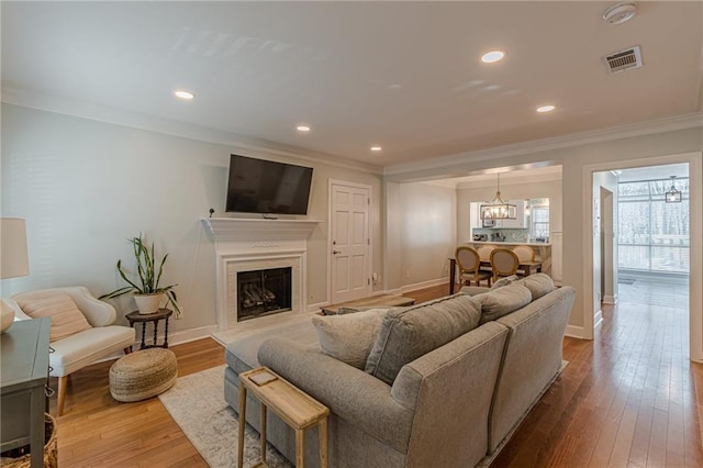 living room featuring hardwood / wood-style floors, an inviting chandelier, and ornamental molding