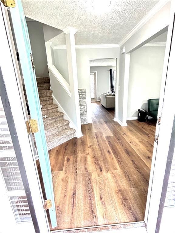 entrance foyer with hardwood / wood-style flooring, ornamental molding, and a textured ceiling