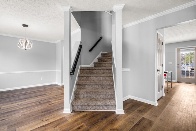 stairway with a textured ceiling, crown molding, baseboards, and hardwood / wood-style floors