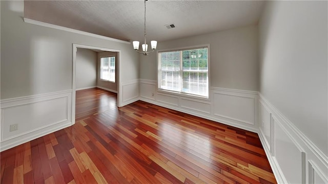 unfurnished dining area featuring an inviting chandelier, a healthy amount of sunlight, and wood-type flooring