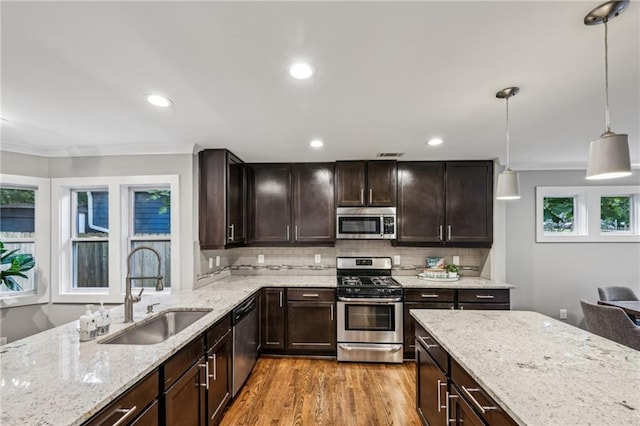 1735 Jobeth Ave SE, Atlanta, GA 30316 - kitchen with stainless steel appliances, ornamental molding, light wood-type flooring, dark brown cabinets, and light stone counters