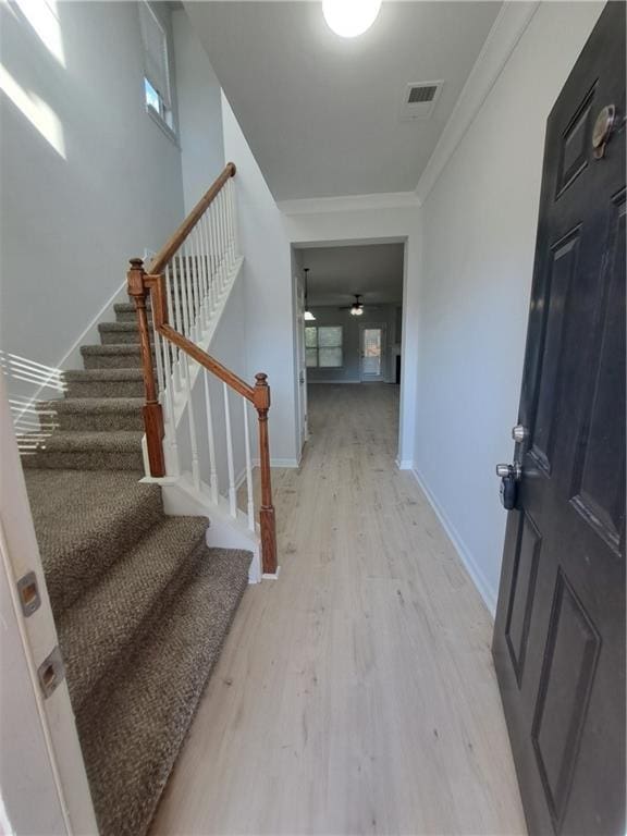 foyer entrance featuring ceiling fan, light wood-type flooring, and ornamental molding