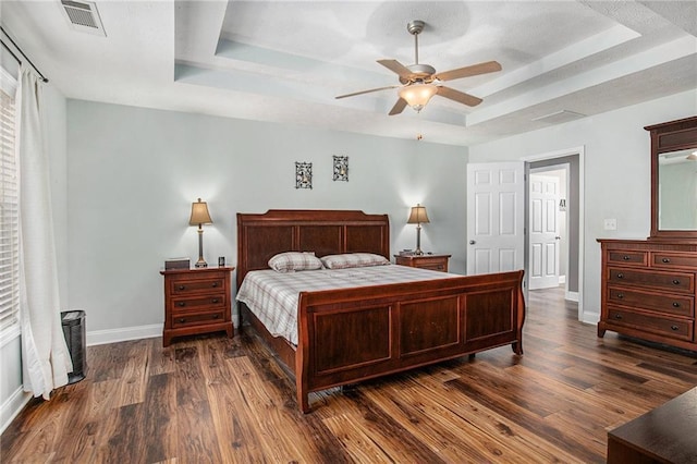 bedroom with visible vents, ceiling fan, baseboards, dark wood finished floors, and a raised ceiling