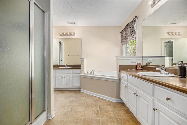 bathroom with a shower stall, baseboards, two vanities, tile patterned floors, and a sink