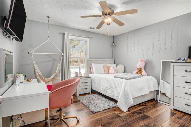 bedroom featuring visible vents, a textured ceiling, dark wood finished floors, and a ceiling fan