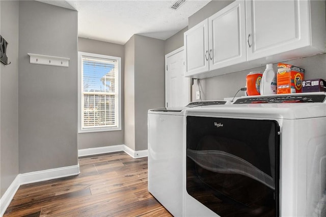 laundry room with visible vents, baseboards, wood finished floors, cabinet space, and separate washer and dryer