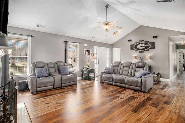 living area with visible vents, lofted ceiling, a healthy amount of sunlight, and wood finished floors