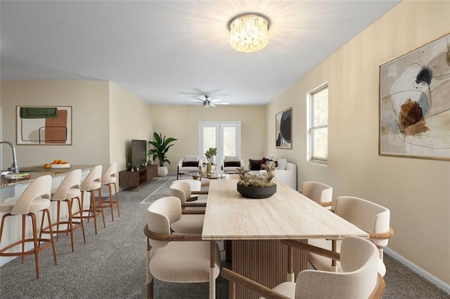 carpeted dining space featuring ceiling fan with notable chandelier