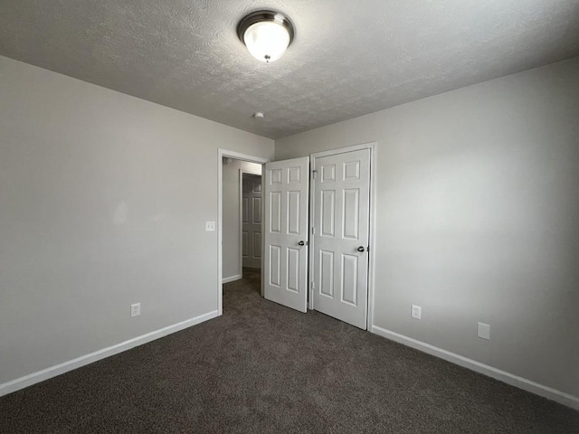 unfurnished bedroom with dark carpet and a textured ceiling