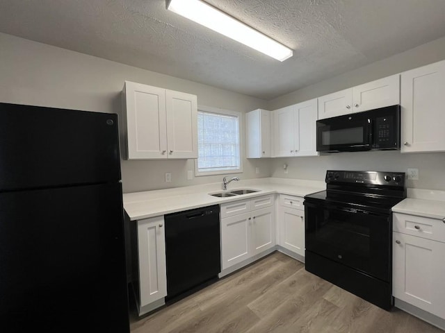 kitchen with white cabinetry, sink, light hardwood / wood-style flooring, and black appliances