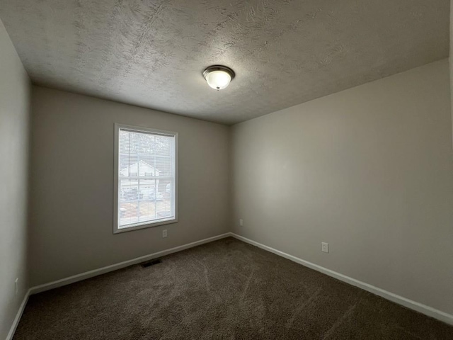 carpeted empty room featuring a textured ceiling