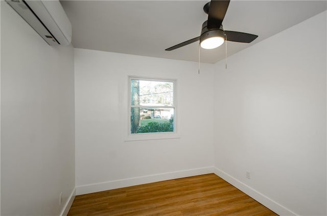 spare room featuring a wall mounted air conditioner, light hardwood / wood-style floors, and ceiling fan