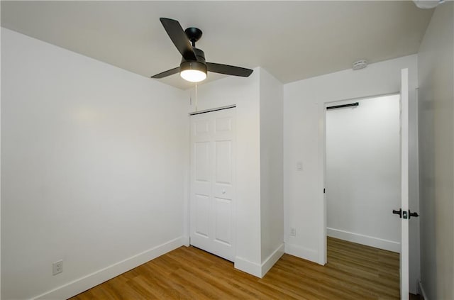 unfurnished bedroom featuring ceiling fan, a closet, and wood-type flooring