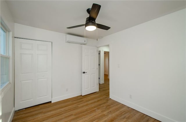 unfurnished bedroom featuring an AC wall unit, ceiling fan, a closet, and light hardwood / wood-style flooring