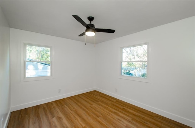 spare room with a wealth of natural light, ceiling fan, and light wood-type flooring