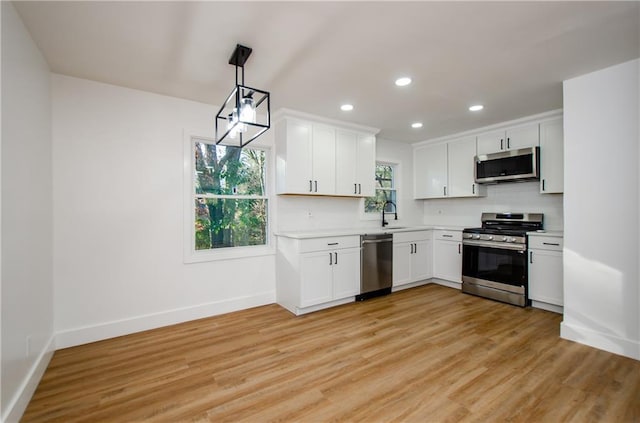 kitchen with white cabinetry, sink, decorative light fixtures, and appliances with stainless steel finishes